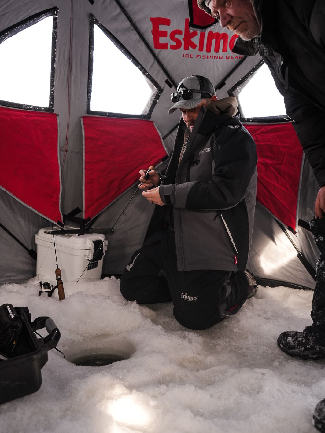 Inside view of a red Eskimo ice fishing shelter with fishing equipment.