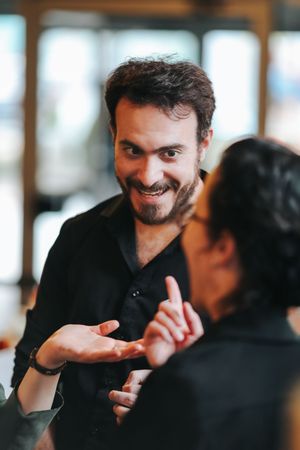 Two people engaged in an animated conversation, with person in black shirt gesturing expressively during discussion.