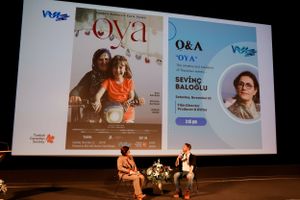 A movie screening event showing a film poster and presentation screen in an auditorium setting.