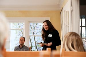 People gathered in a bright room with windows during what appears to be a professional or educational meeting.