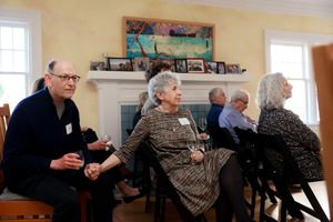 Seniors socializing together in a bright living room with yellow walls and a white fireplace in the background.