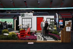 Architectural exhibit display showcasing a modern storefront design with red chairs and colorful flower arrangements.