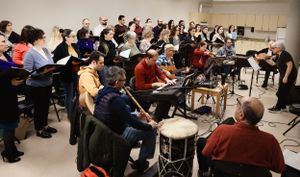 Music students with instruments gather in a classroom setting for band practice or rehearsal.