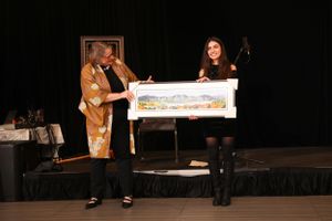 Two people on stage with a large presentation check during an award ceremony or recognition event.