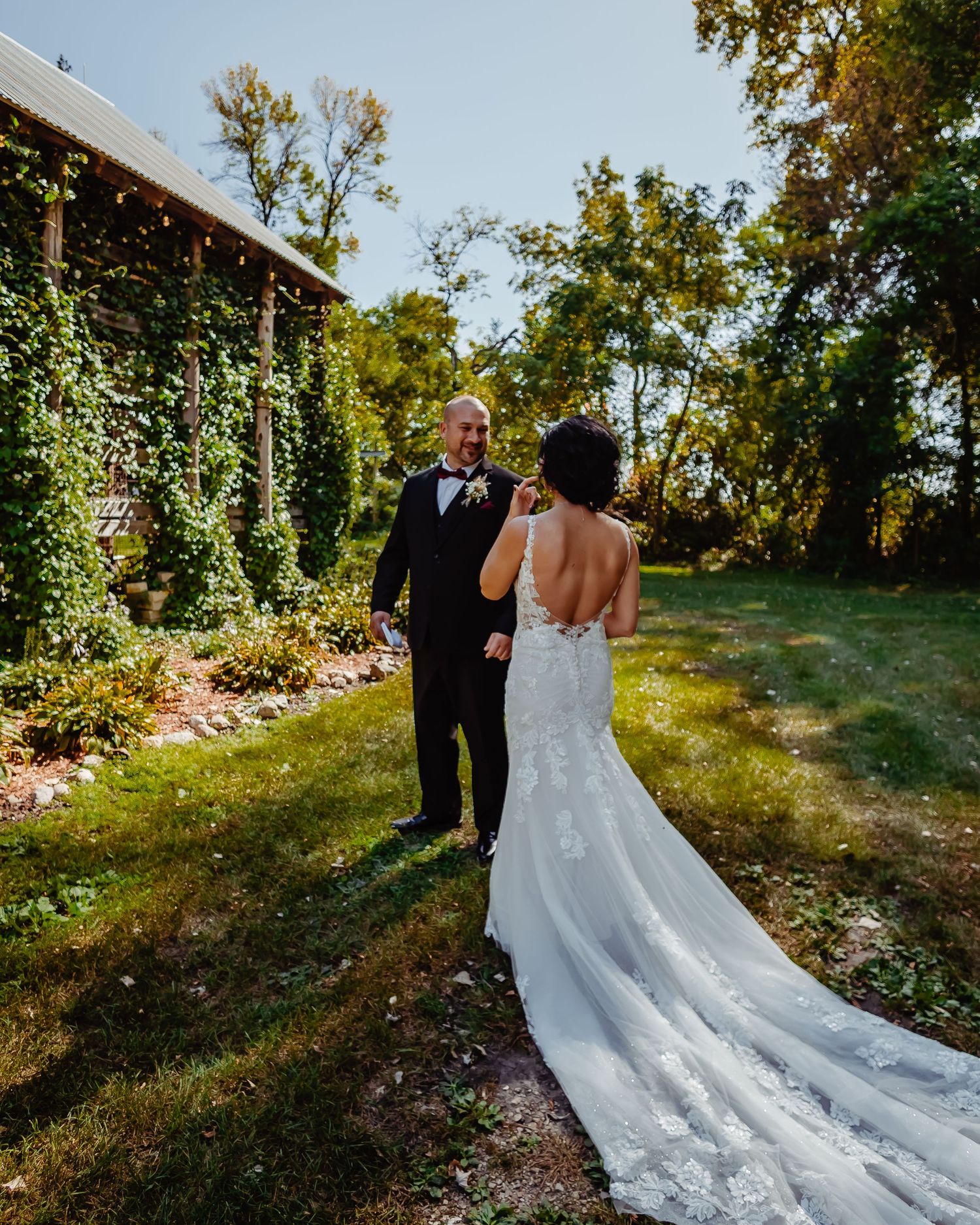 A stunning outdoor wedding scene with romantic natural lighting and lush greenery surrounding formal attire and a trailing gown.