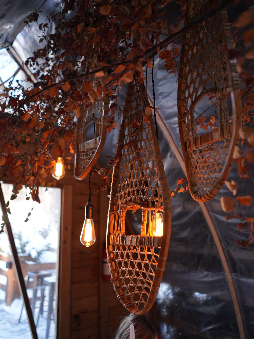 Decorative macrame lanterns and string lights hanging against snowy winter backdrop.