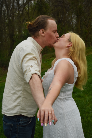A romantic couple sharing a tender kiss outdoors in a natural green setting.