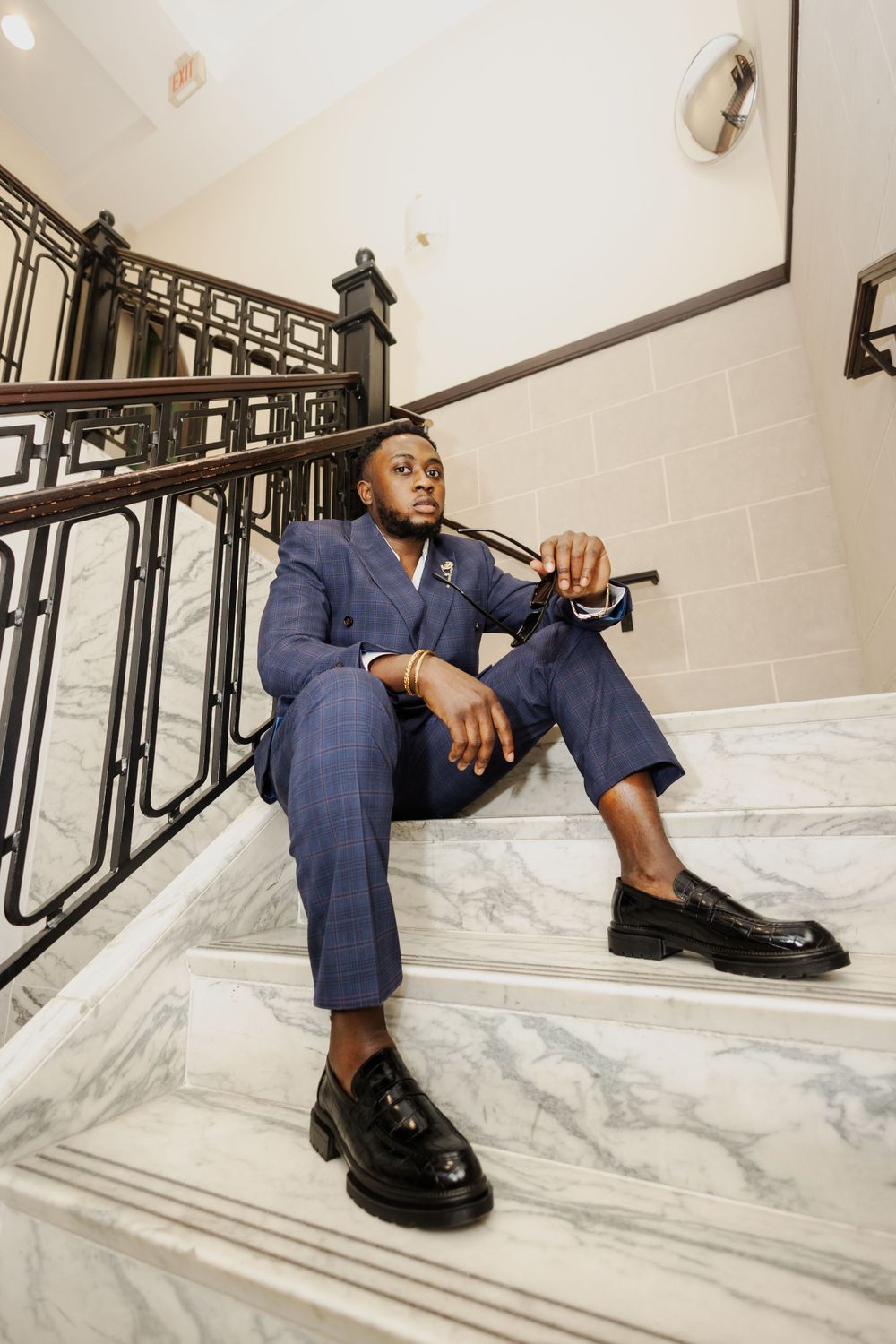 Person in navy suit lounges on marble staircase.