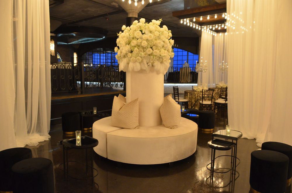 Contemporary white circular display pedestal with floral arrangement in an event space.