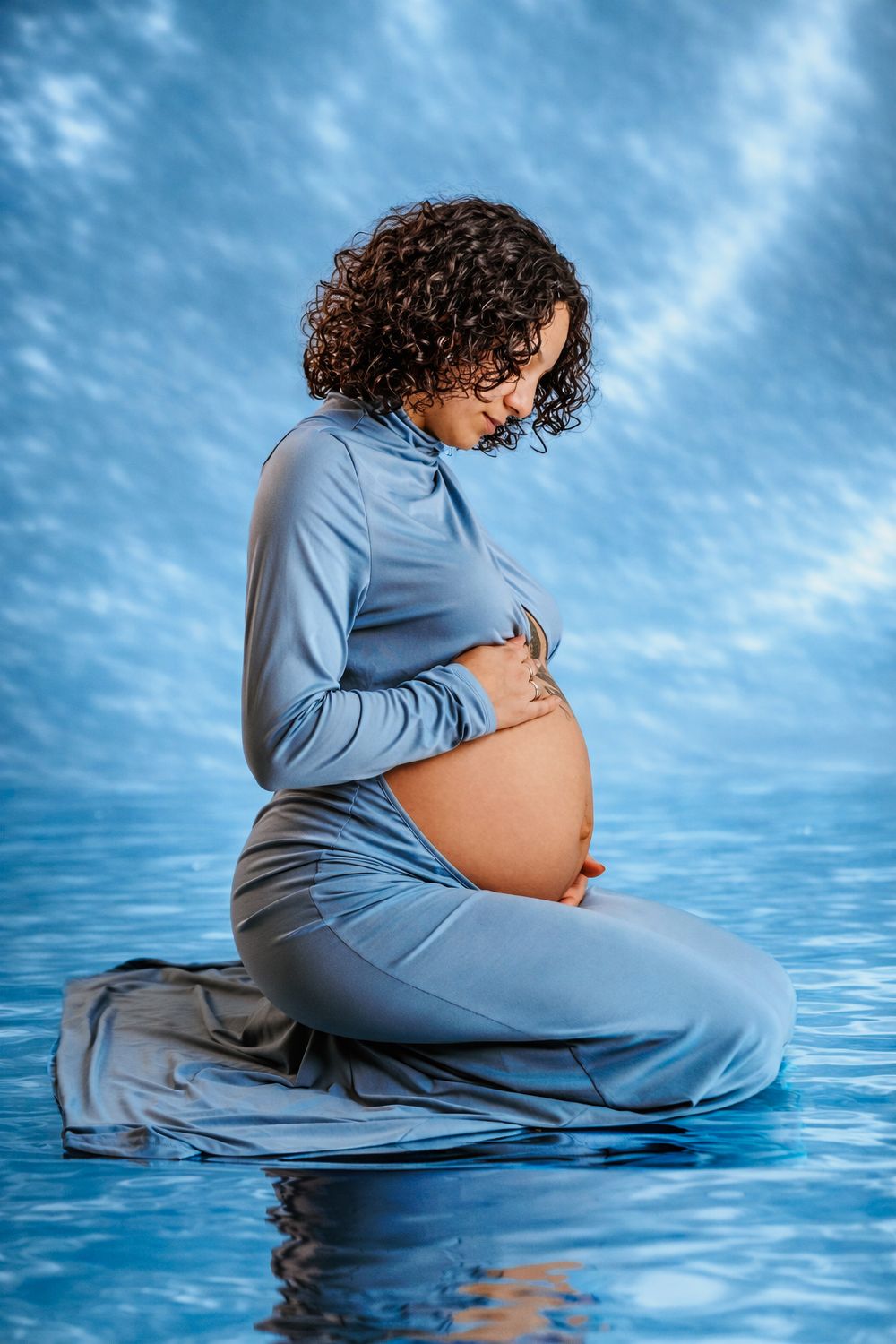 Maternity photoshoot sequence in blue tones showing pregnancy silhouette near water.