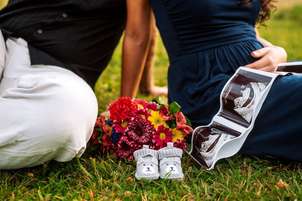 Wedding details showing white dress fabric and red floral bouquet elements against green grass.