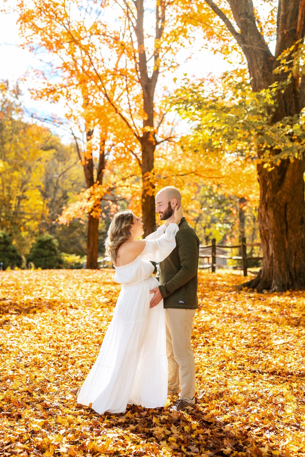 Couple twirls and dances on a carpet of golden fall leaves in a park.
