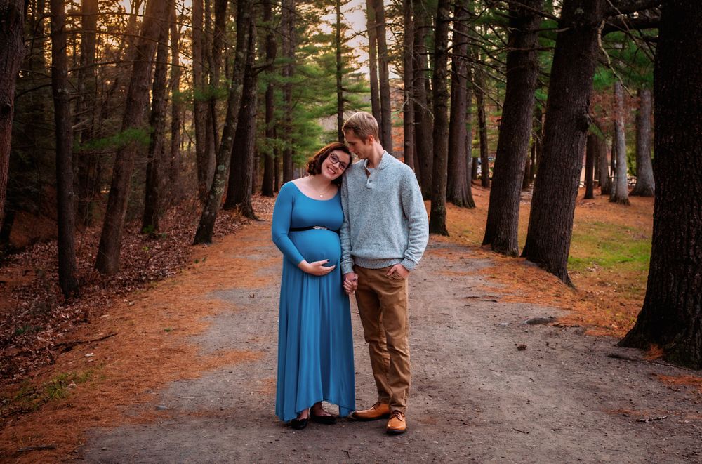 Couple embracing on forest trail during golden hour photography session.