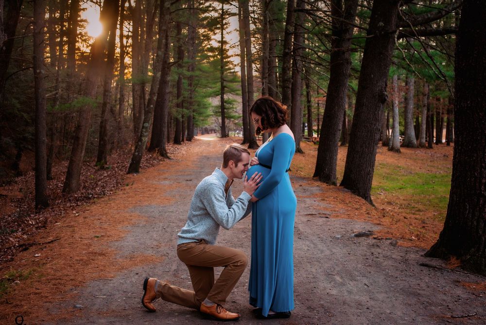 Couple embraces on a wooded path during golden sunset.