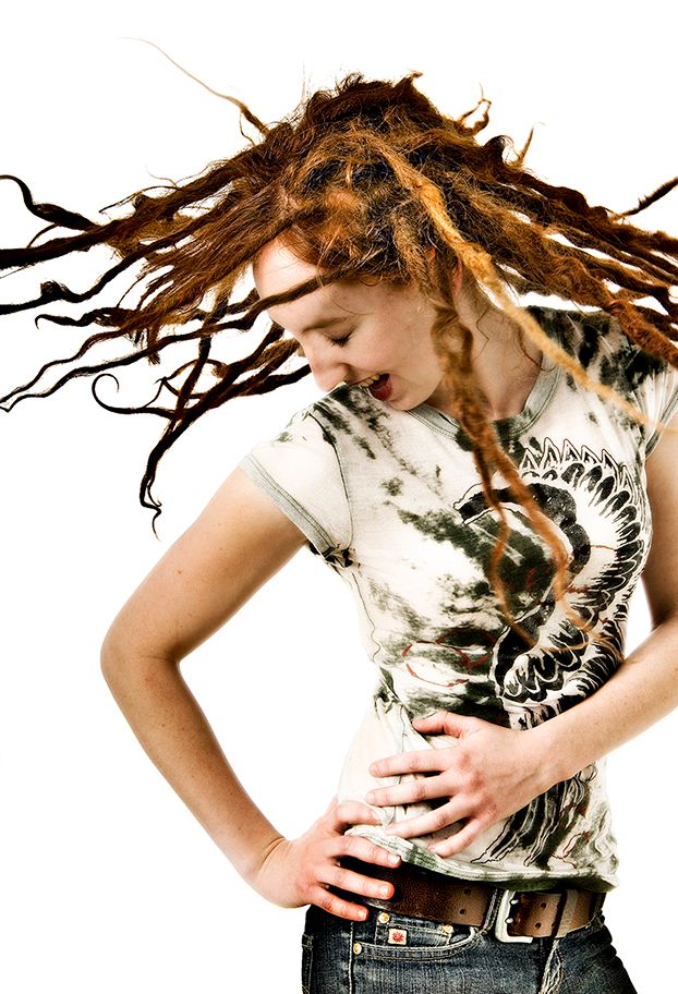 A person with long dreadlocks whips their head sideways while wearing a graphic t-shirt and belt. (Parma New York)
