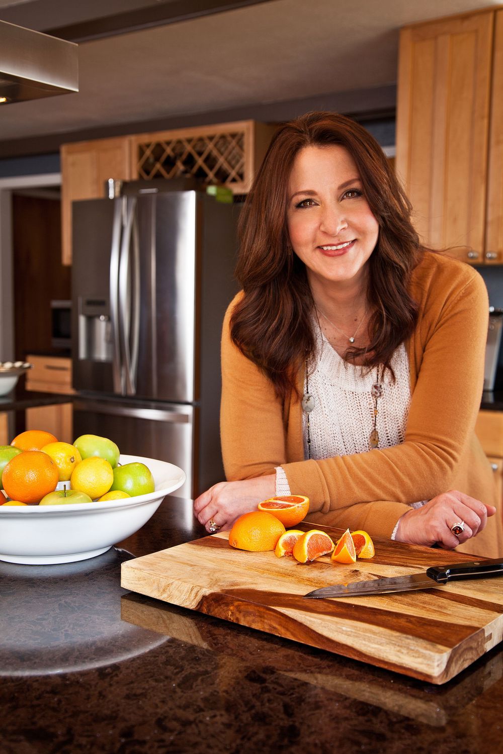 A woman prepares fresh citrus fruits on a wooden cutting board in a modern kitchen with stainless steel appliances. (Pittsford New York)
