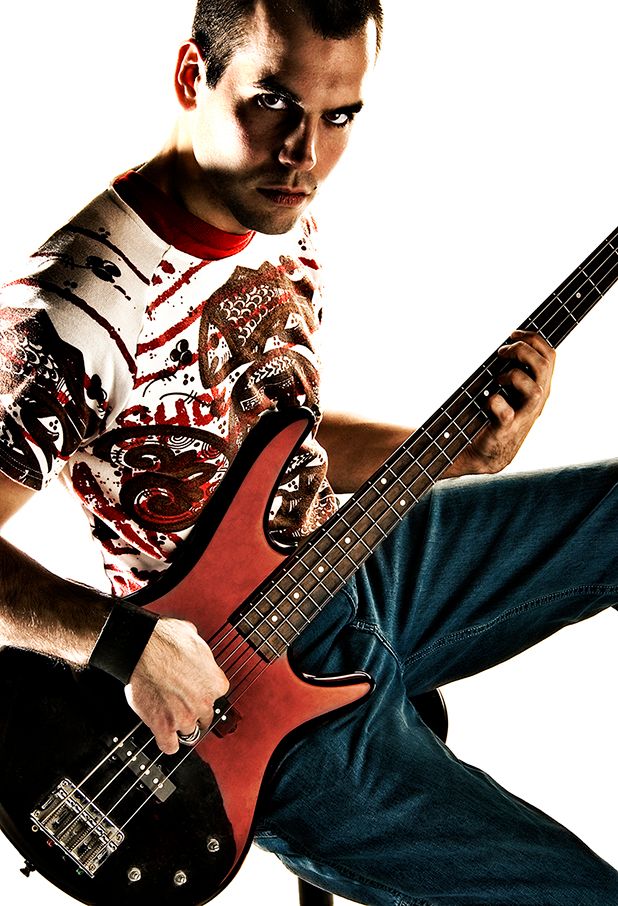 Musician in blood-spattered white t-shirt plays red electric bass guitar against white backdrop. (East Rochester New York)