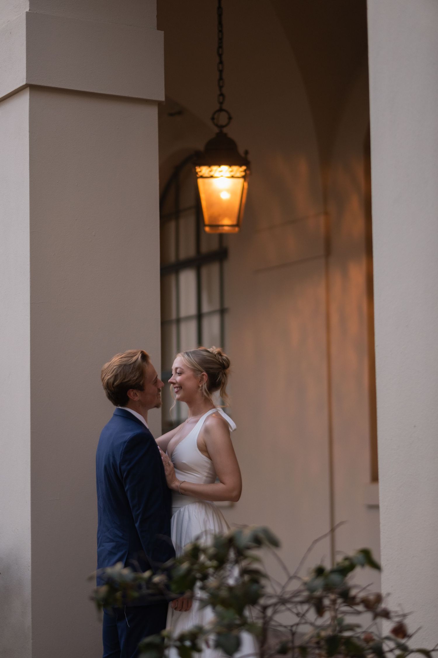 A couple shares an intimate moment under warm lighting in an archway.