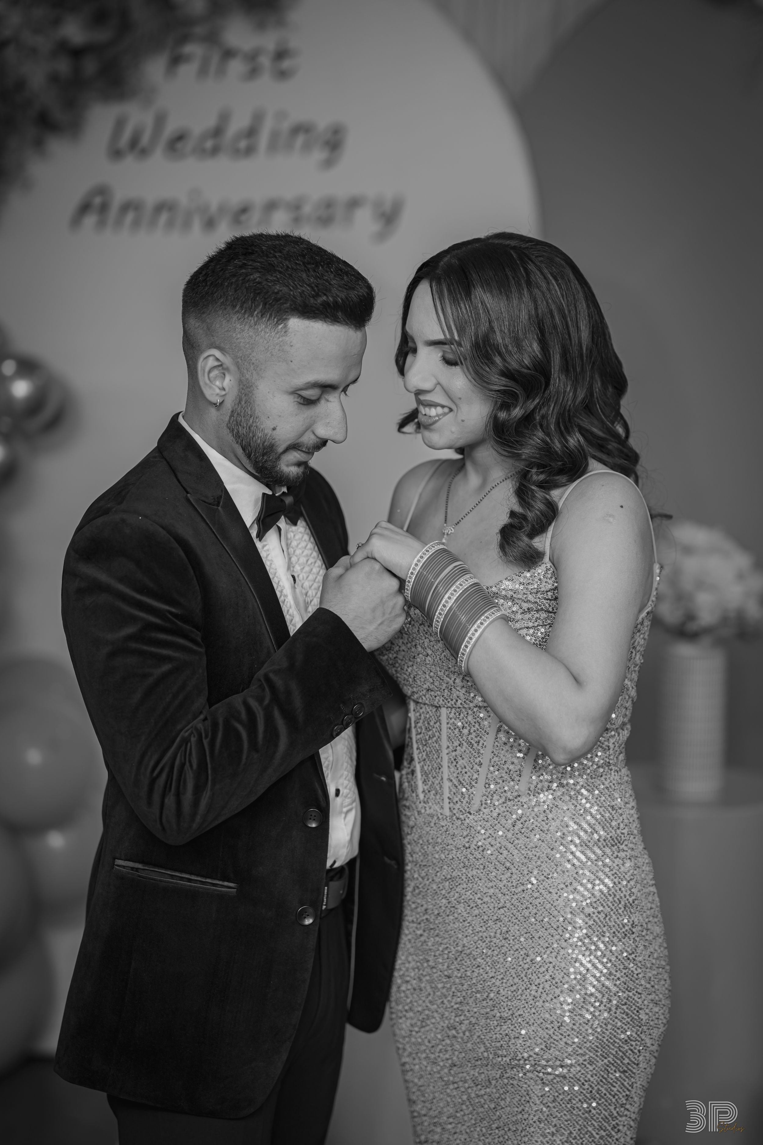 A couple shares an intimate moment on their wedding day, with the bride wearing a sparkly dress and groom in black tuxedo.