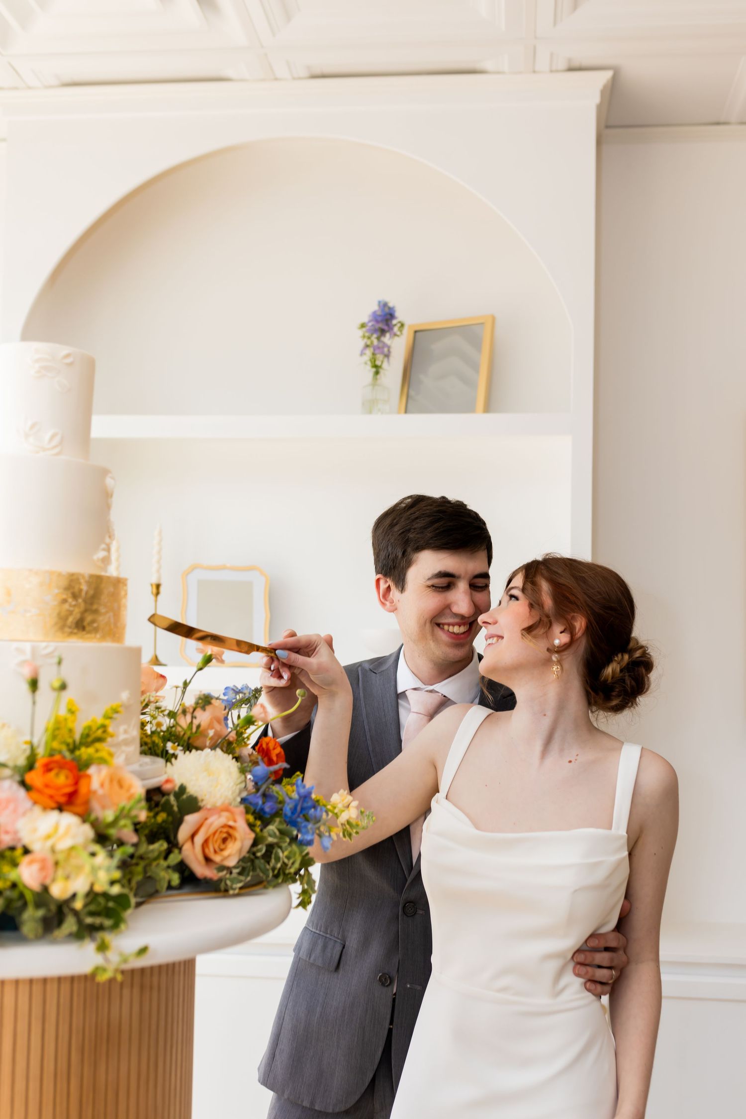 Bride and groom laughing while cutting their wedding cake at a modern Utah wedding venue