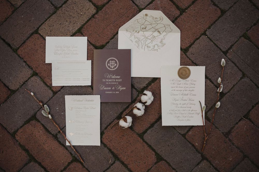 Wedding invitations and stationery laid out on red brick pavers.