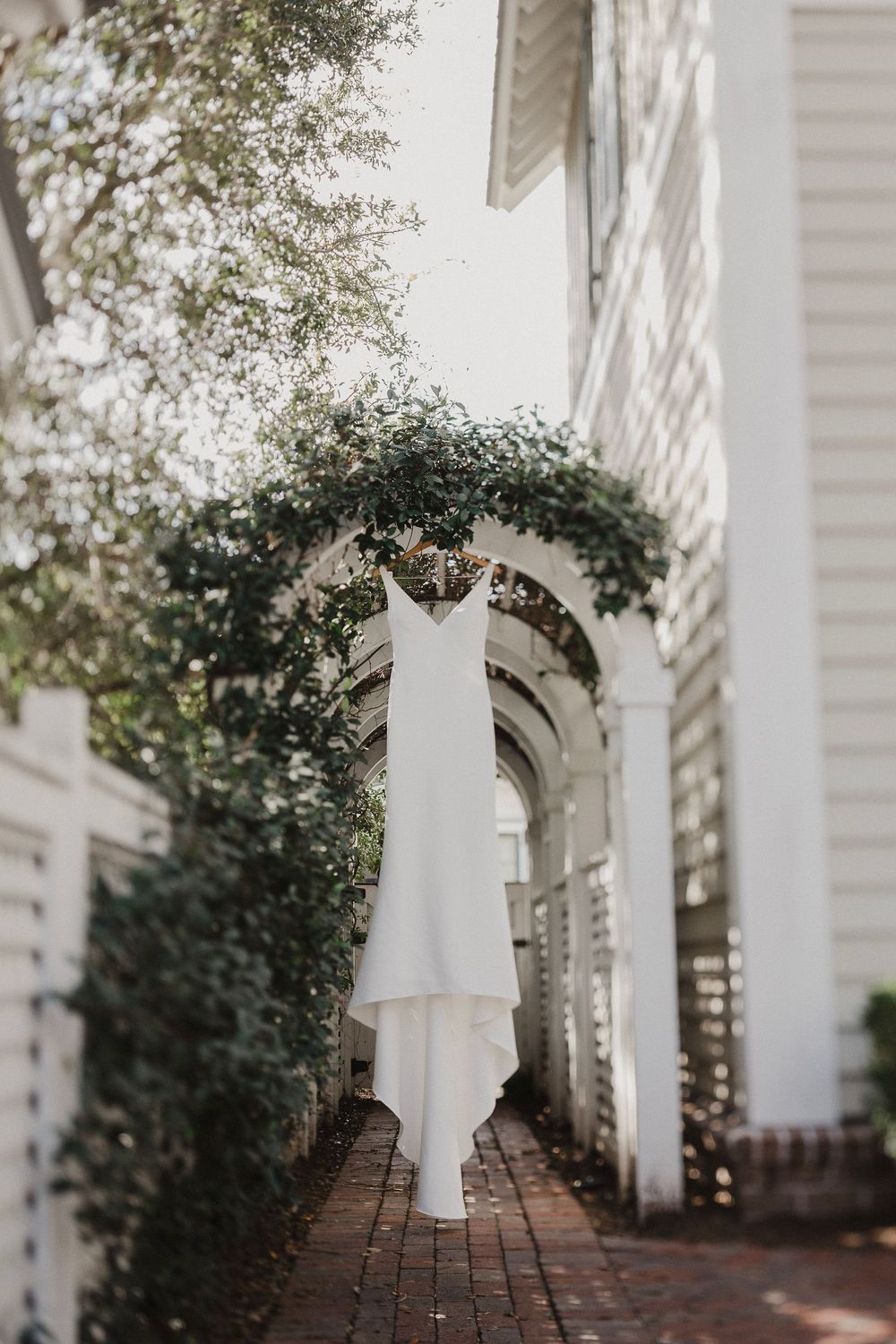 White pillars and brick pathway create an elegant outdoor walkway with natural lighting.