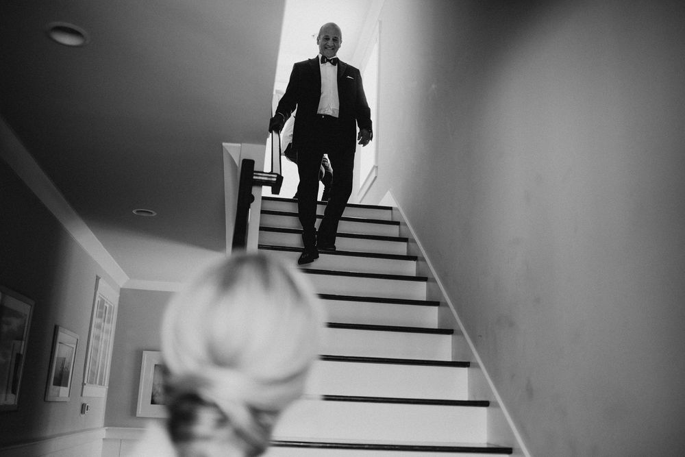 Black and white photo of someone descending stairs while another watches from below.