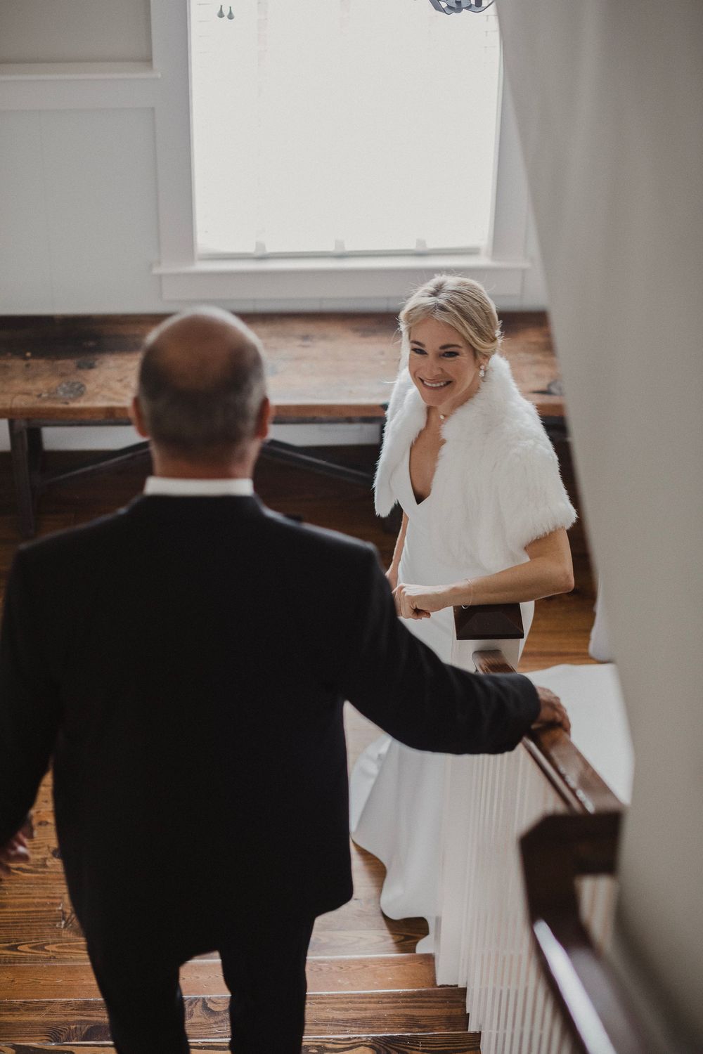 Wedding day moment captured on wooden staircase in intimate setting.