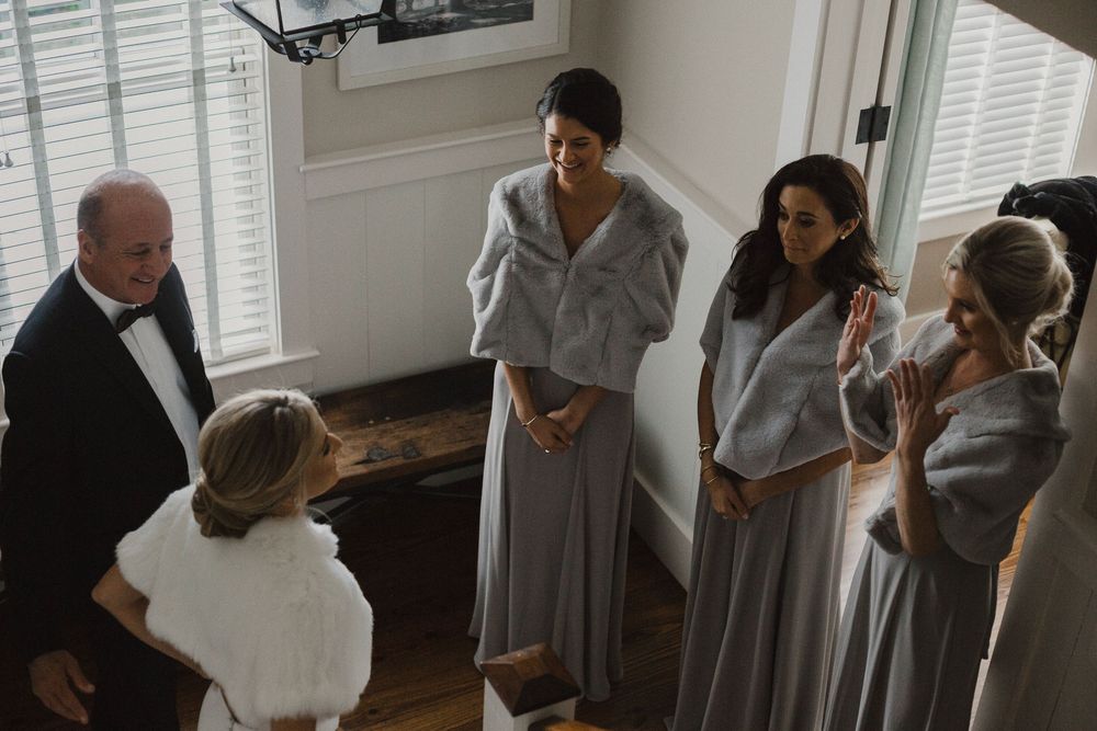Wedding party gathered in casual moment before ceremony in sunlit room.