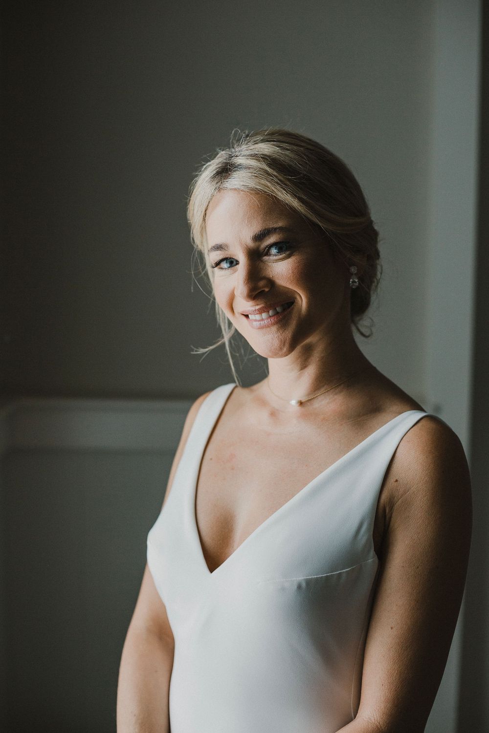 Elegant bridal portrait in simple white v-neck dress with natural lighting.