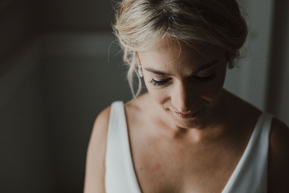 Intimate portrait of bride in white v-neck dress with natural lighting.