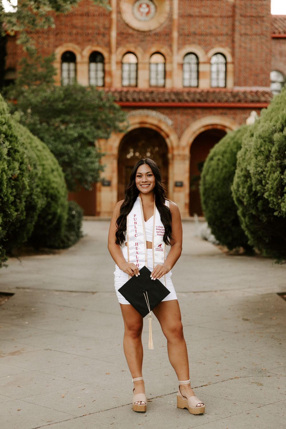 A graduation photo session outside a historic red brick university building with arched architecture.