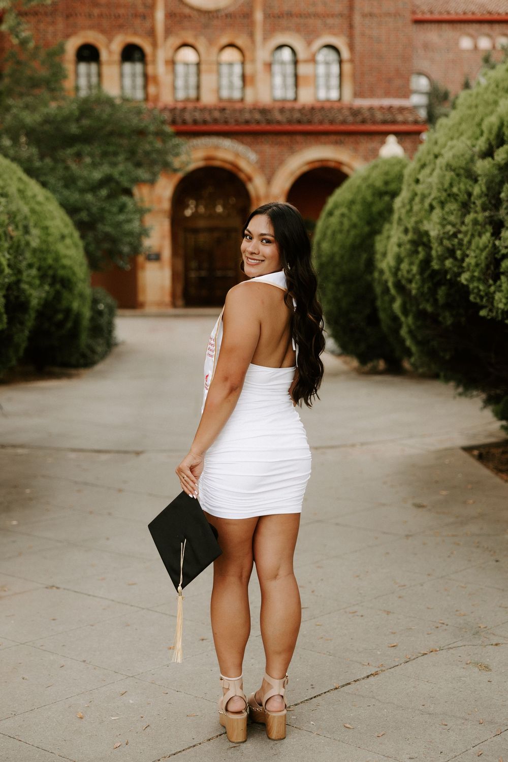 A series of outdoor graduation photos taken at a university building with arched architecture and landscaped grounds.