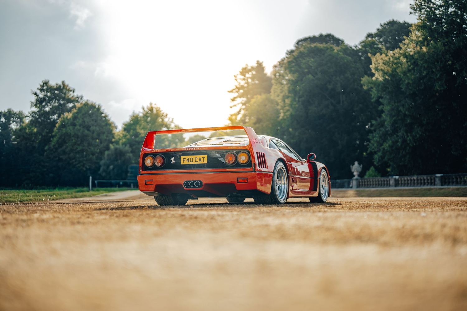 Vintage orange sports car parked in a scenic outdoor setting during golden hour.