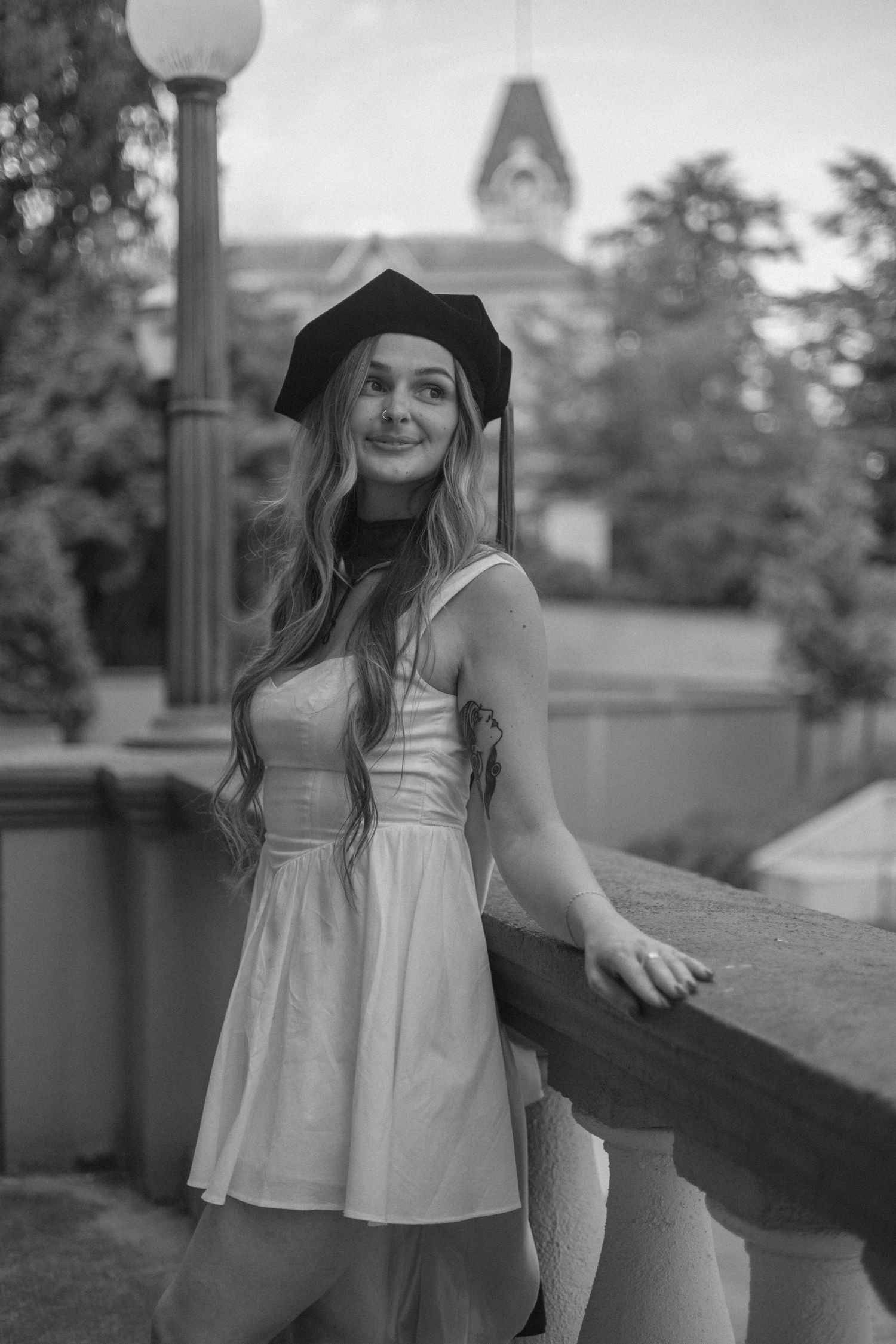 A black and white photo series showing someone in a black dress posing against architectural columns in sunlight.