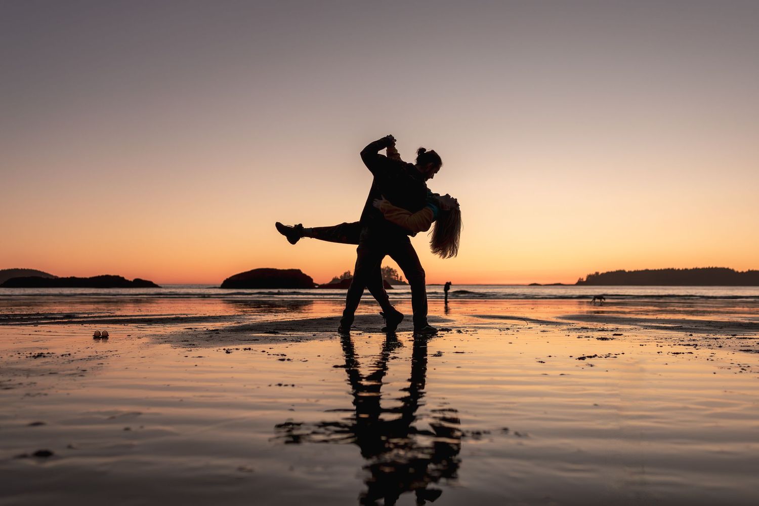 a couple dancing in the sunset on a beach