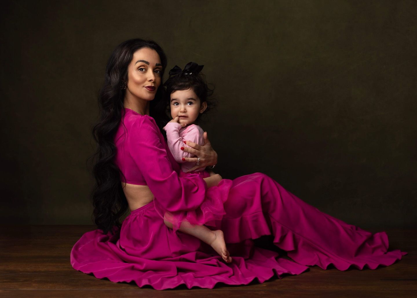 A series of photos showing people in matching magenta dresses posing on a dark wooden floor against a black background.