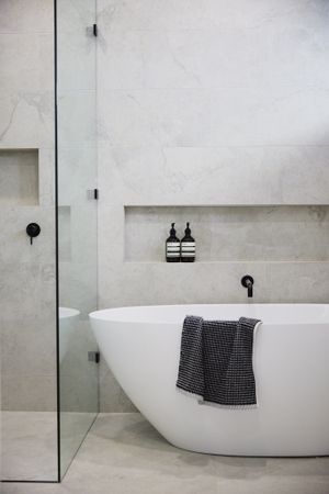 Contemporary bathroom with freestanding white tub, glass shower partition and built-in wall niche.
