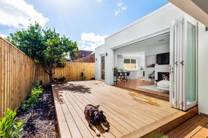 Wooden deck connecting to interior through sliding glass doors with garden landscaping.