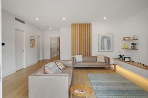 Modern living room with wooden accent wall, grey sofa and minimalist decor on floating shelves.