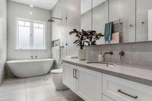 Bright bathroom with freestanding tub, white vanity and textured tile walls.