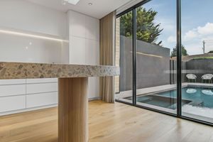 Modern kitchen interior with hardwood floors and sliding glass doors overlooking a swimming pool.