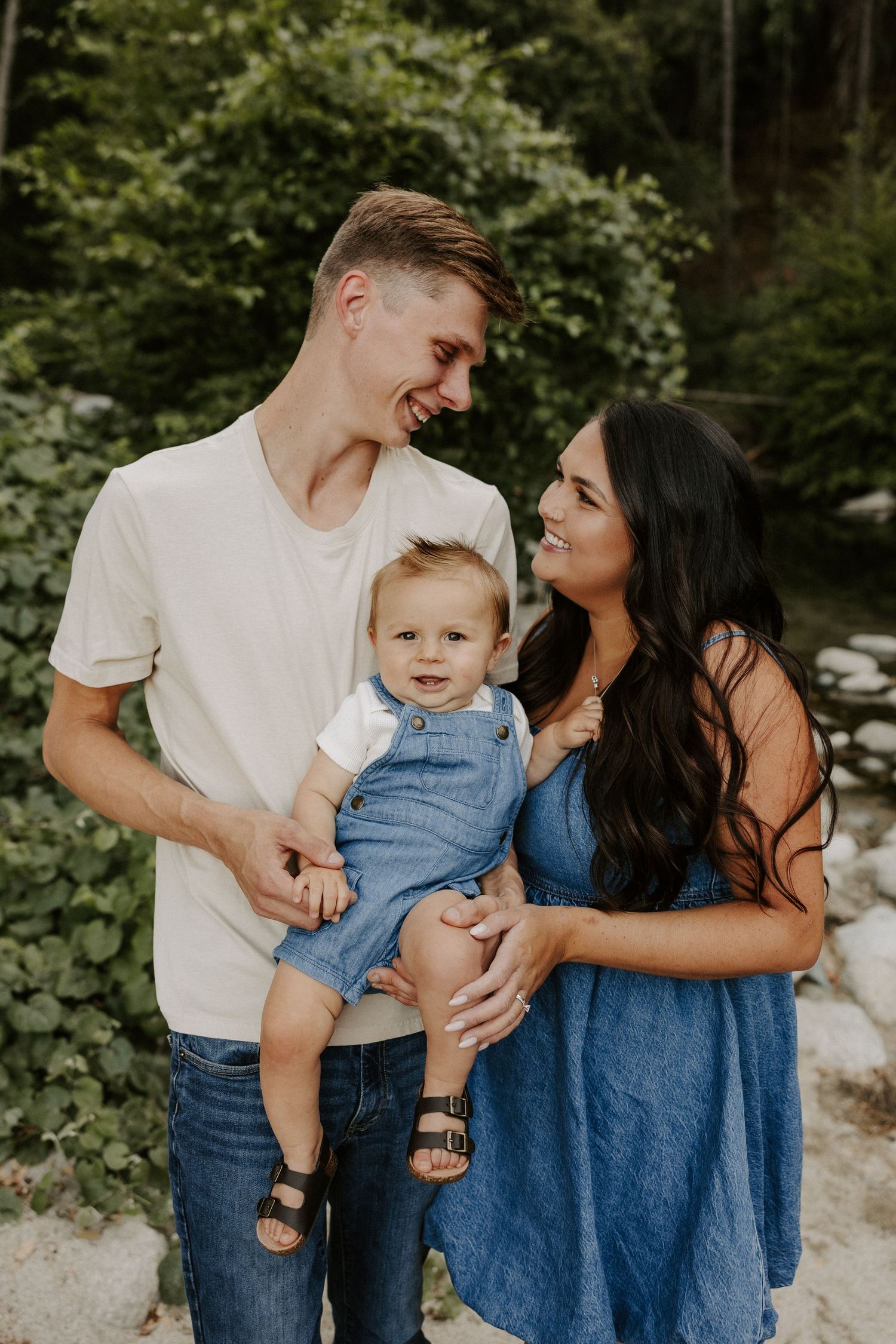 A family in coordinated blue and white outfits shares loving moments together in an outdoor photoshoot.