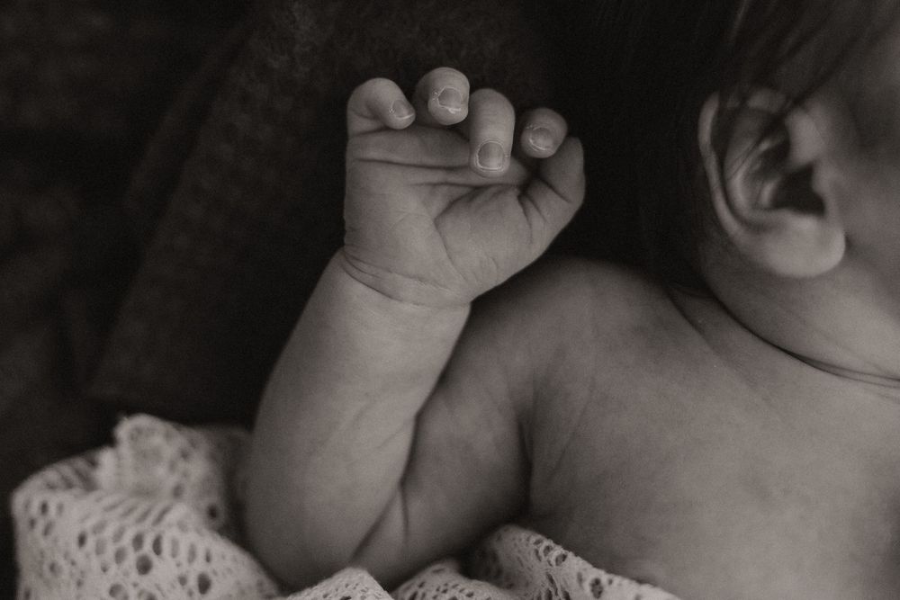 A series of intimate black and white photographs showing tender moments between a parent and newborn baby.