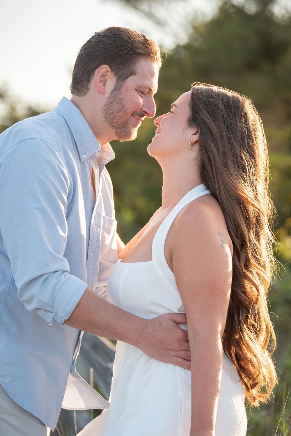 Loving couple in white and blue sharing romantic moments during golden hour photoshoot.