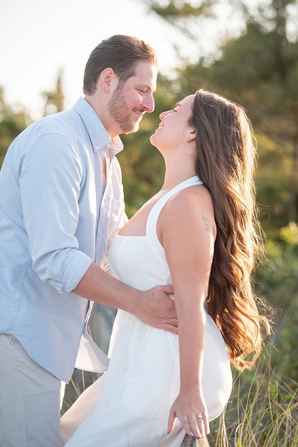 Sweet couple embracing in natural setting with sunset glow behind them.