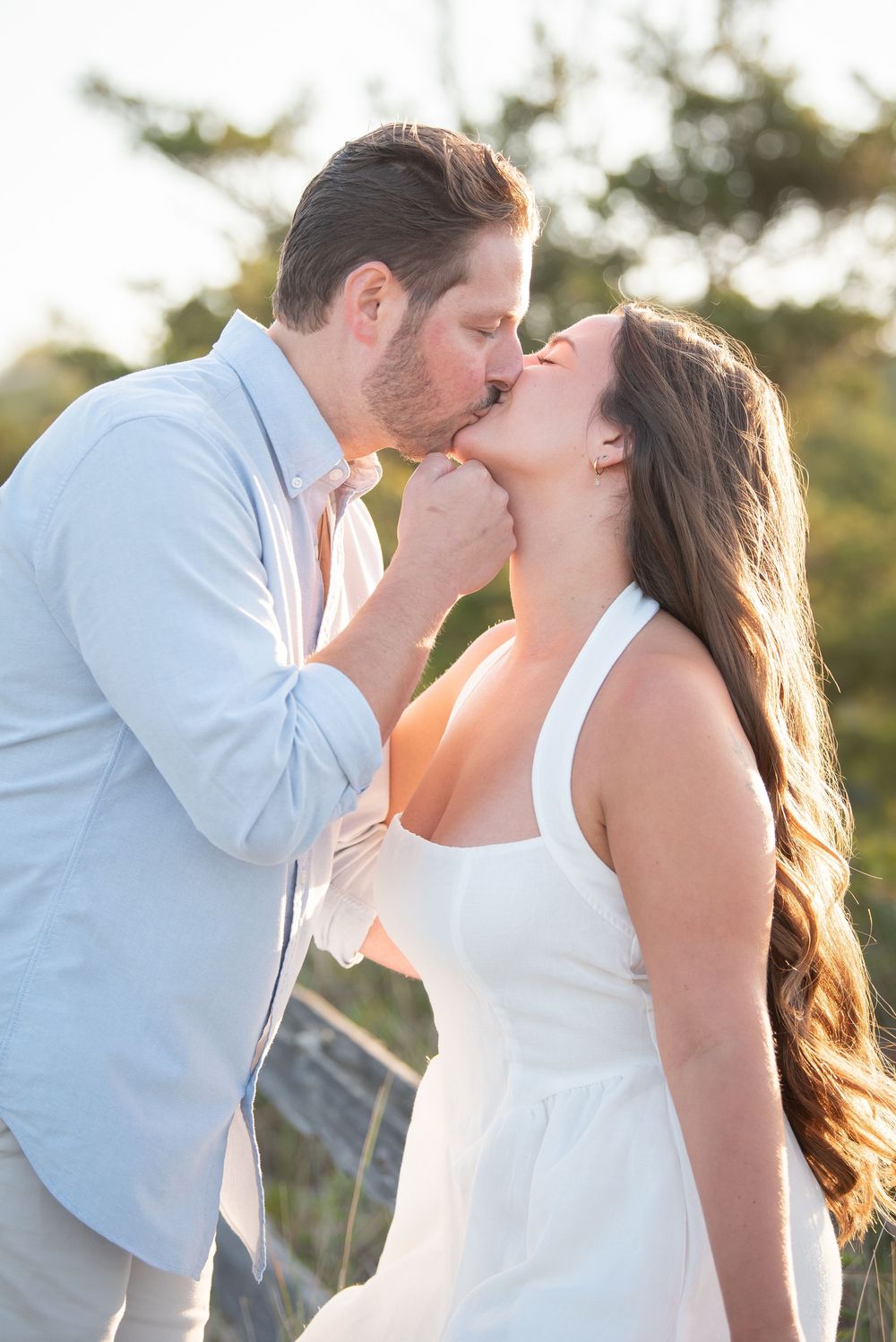 Romantic seaside photoshoot of couple sharing intimate kisses in summer attire.