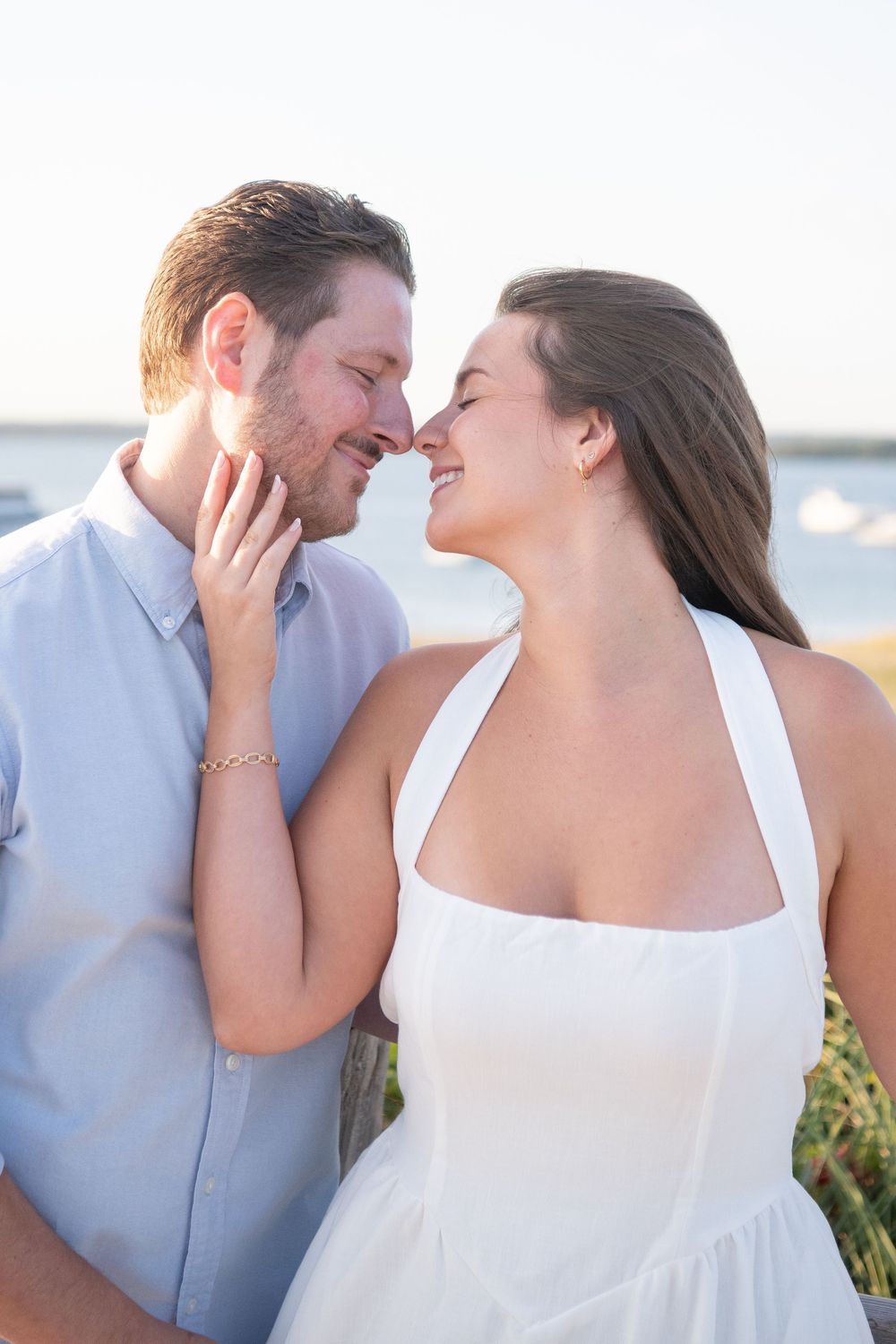 Joyful couple laughing and embracing during beachside photo session.