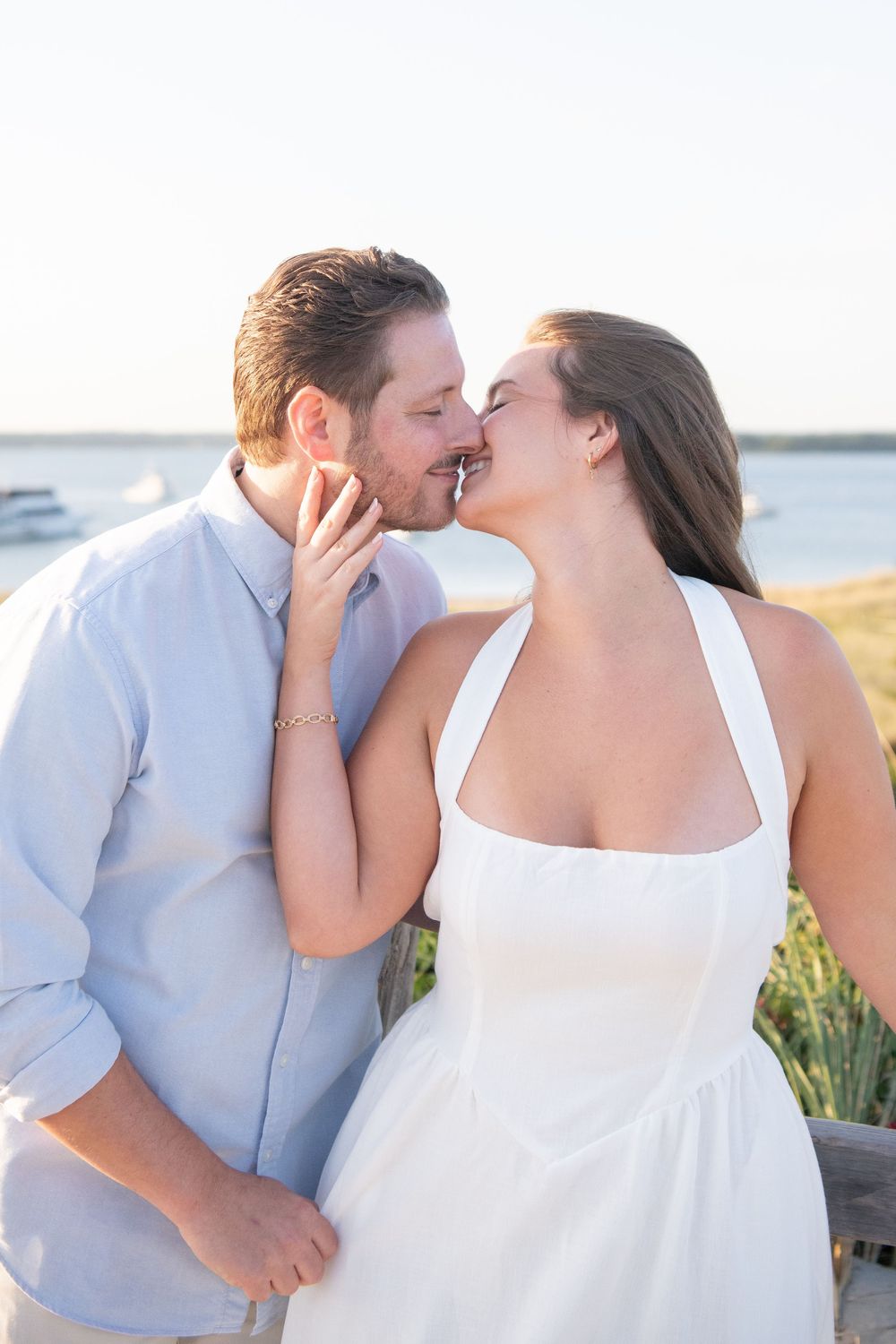 Romantic waterfront photography session with couple in coordinated white and blue outfits.