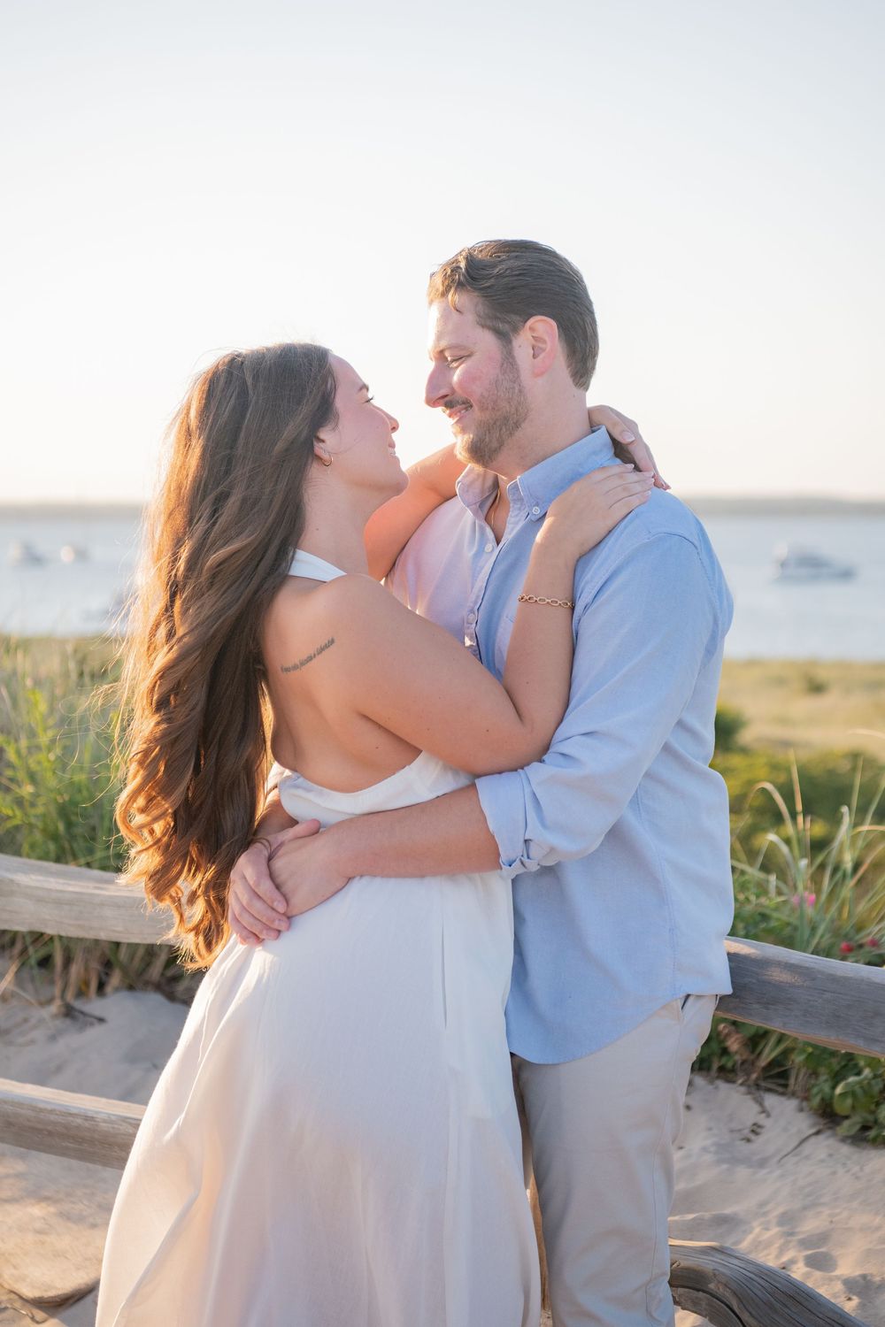 Tender beach photoshoot captures couple's romantic moments against Rhode Island coastal scenery.